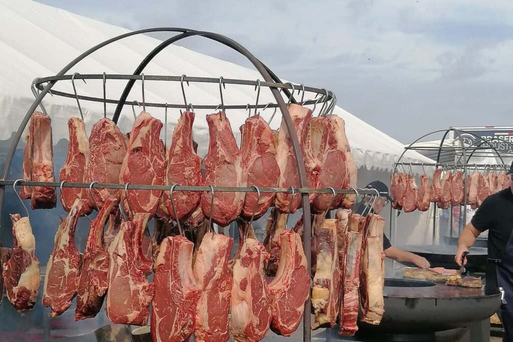 Cage pour braséro garnie de côtes de bœuf suspendues, lors d'un évènement