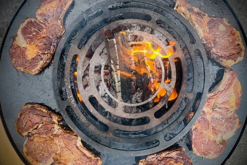 Côtes de bœuf en couronne autour du foyer enflammé, vue du dessus d'un braséro