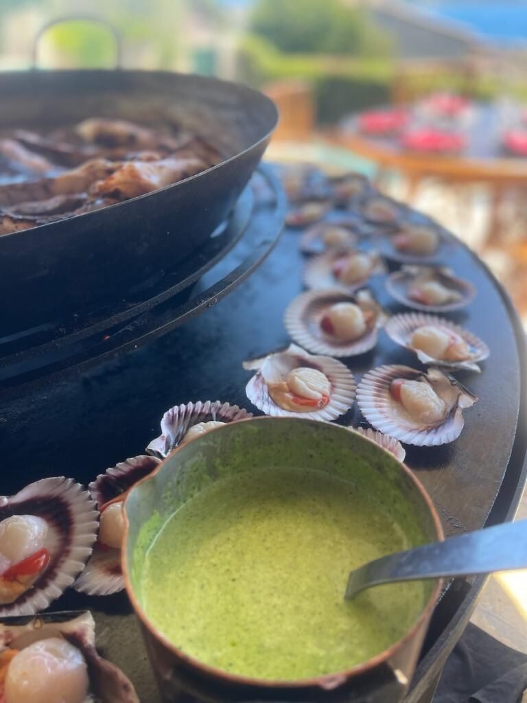 Coquilles Saint-Jacques et beurre vert dans une casserole, sur la plancha