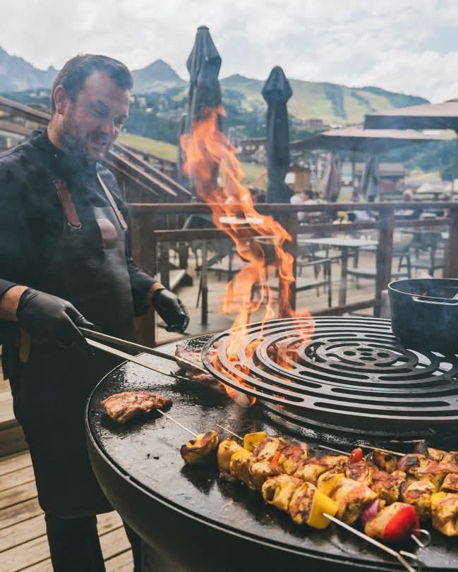 Cuisinier devant la flamme, brochettes grillées sur la plancha
