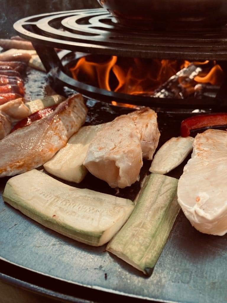 Filets de poulet et lamelles de courgette près de la grille en spirale et des flammes