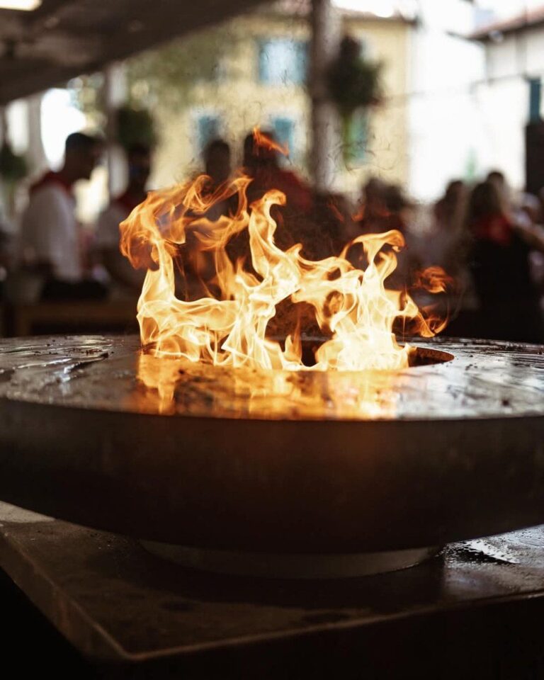 Flamme sur le plateau d'un braséro, terrasse animée en arrière-plan