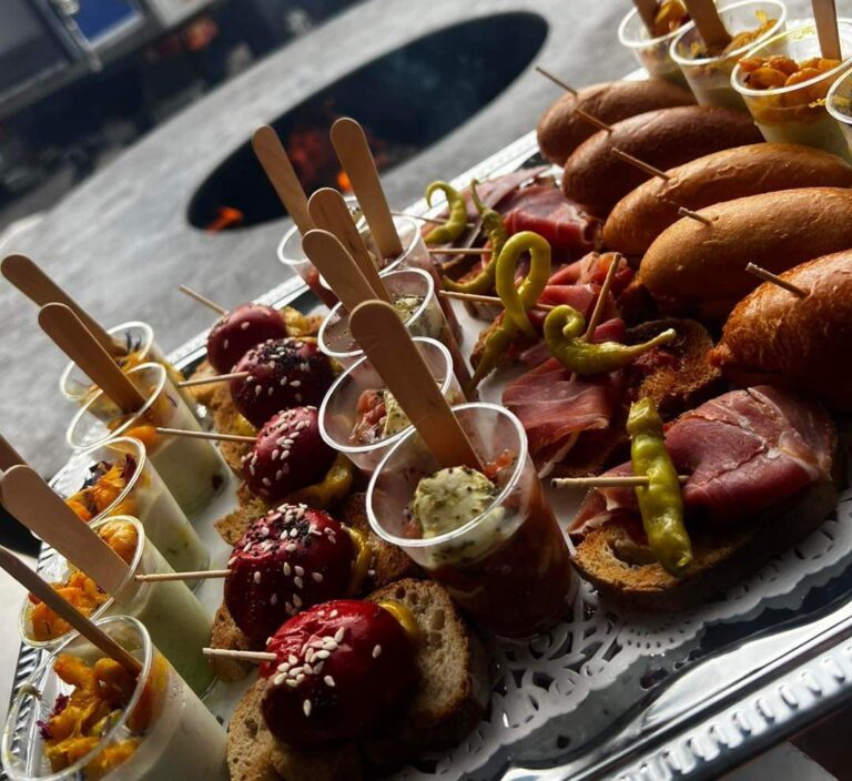 Plateau de bouchées apéritives et de mini burgers posé sur le braséro de 150, foyer en arrière-plan