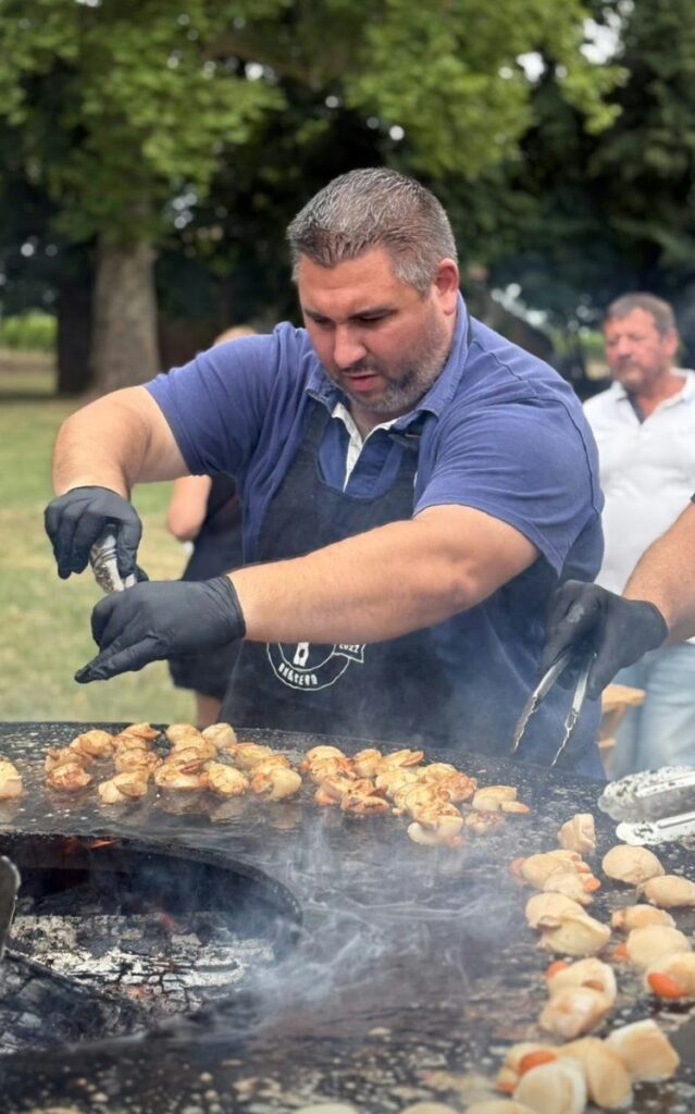 Cuisinier préparant pommes de terre et viandes sur un braséro de 150, en évènement