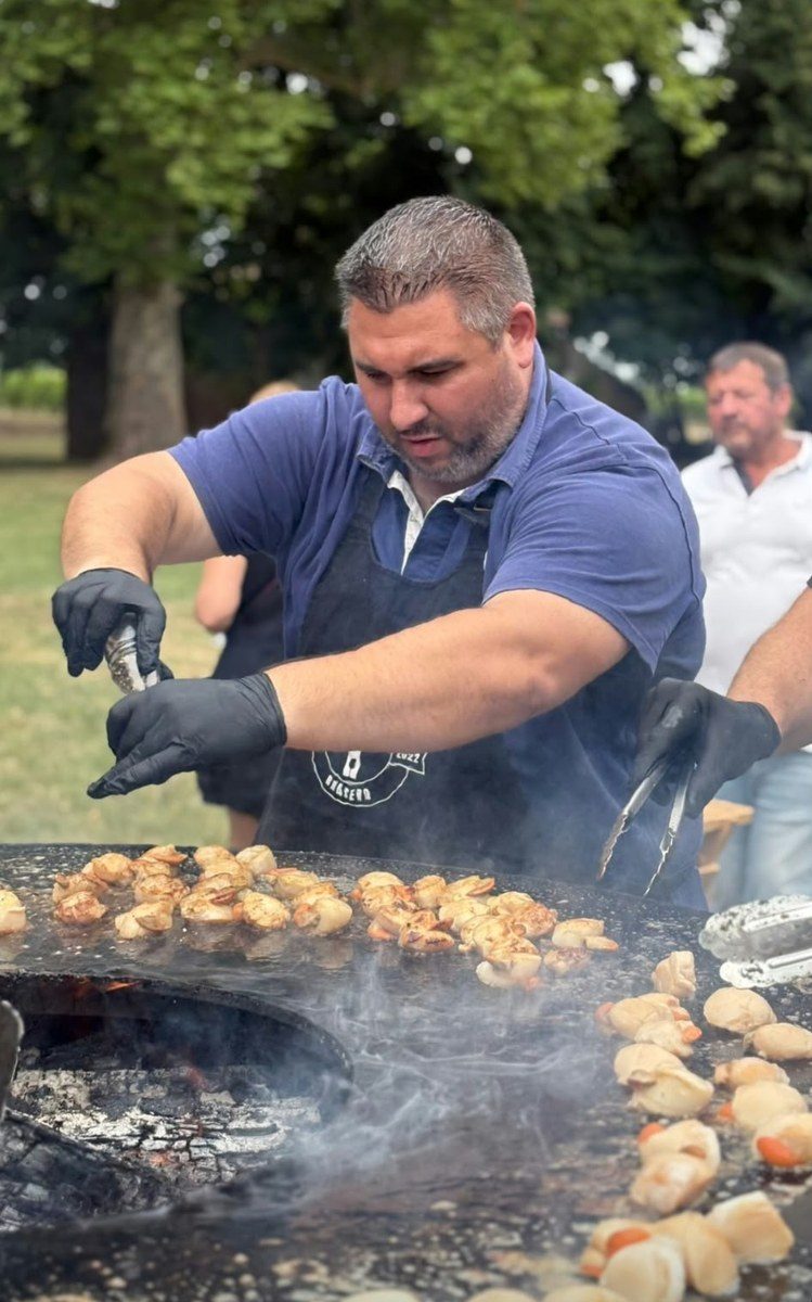 Cuisinier préparant pommes de terre et viandes sur un braséro de 150, en évènement
