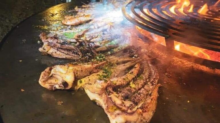 Poissons et pièces de bœuf grillés devant le foyer d'un braséro de 150