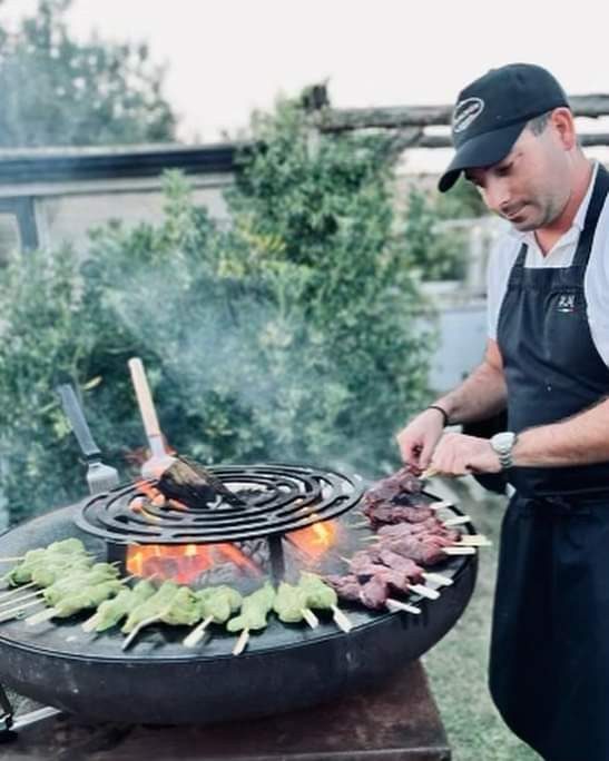 Cuisinier à la casquette grillant des brochettes sur un braséro de 80