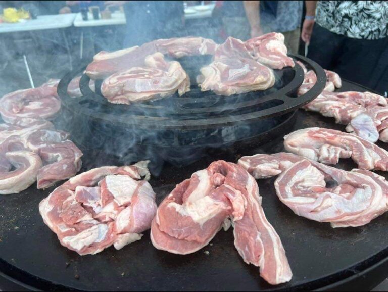 Poitrine et côtes de porc crues autour de la grille en couronne sur la plancha d'un braséro rond de 80