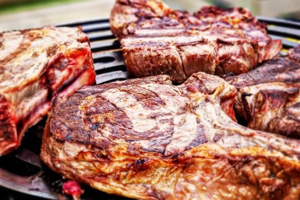 Côtes de bœuf grillées sur la grille d'un braséro, gros plan sur la croûte dorée