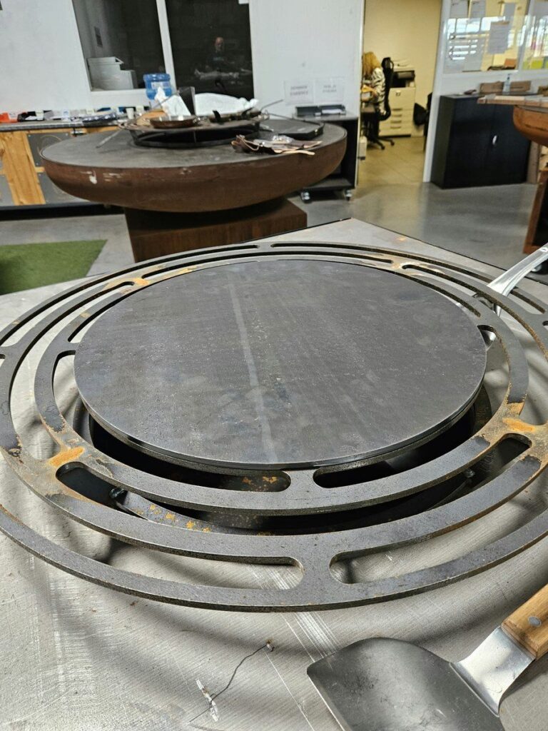 Crêpière simple en acier posée sur la grille d'un braséro