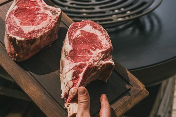 Deux côtes de bœuf maturées sur une planche, près de la grille en spirale