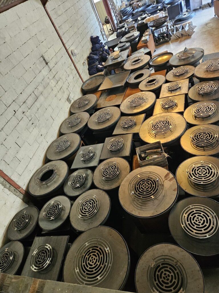 Plateaux de braséros et grilles en spirale rangés à l'atelier