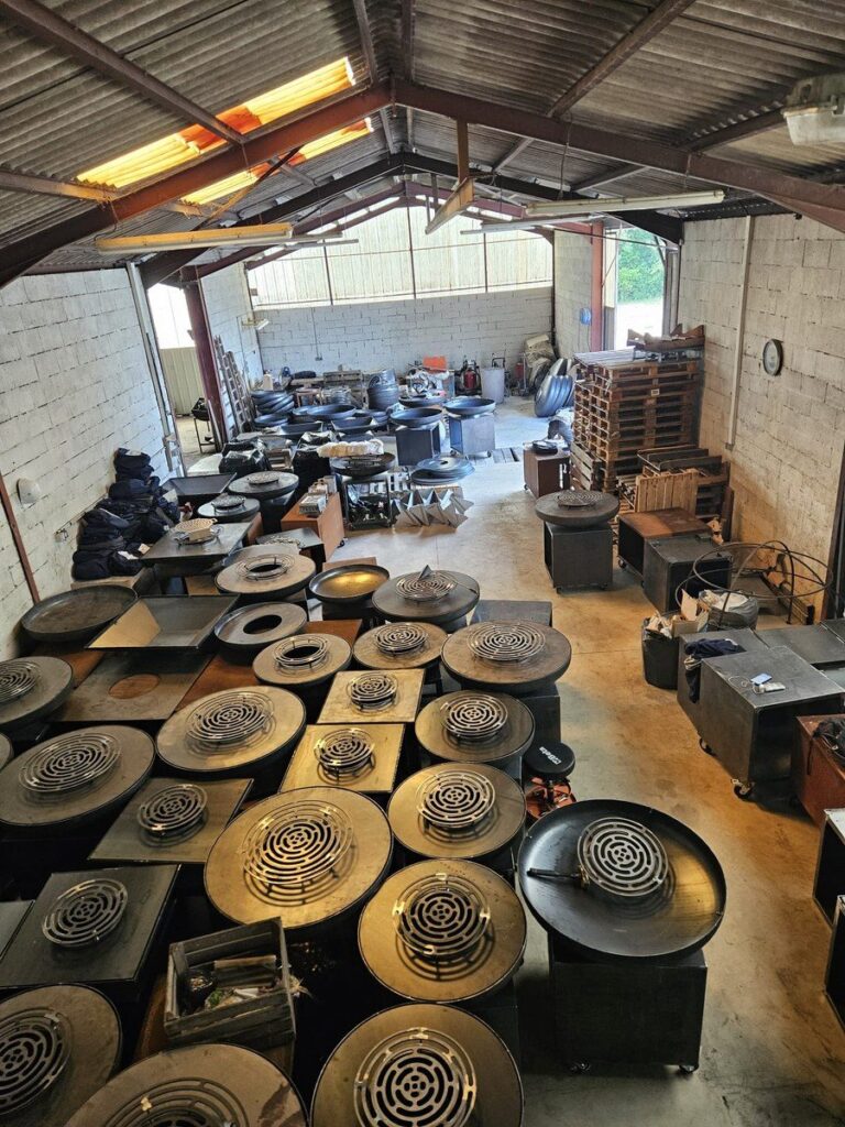 Vue d'ensemble de l'atelier : des dizaines de plateaux de braséros en fabrication