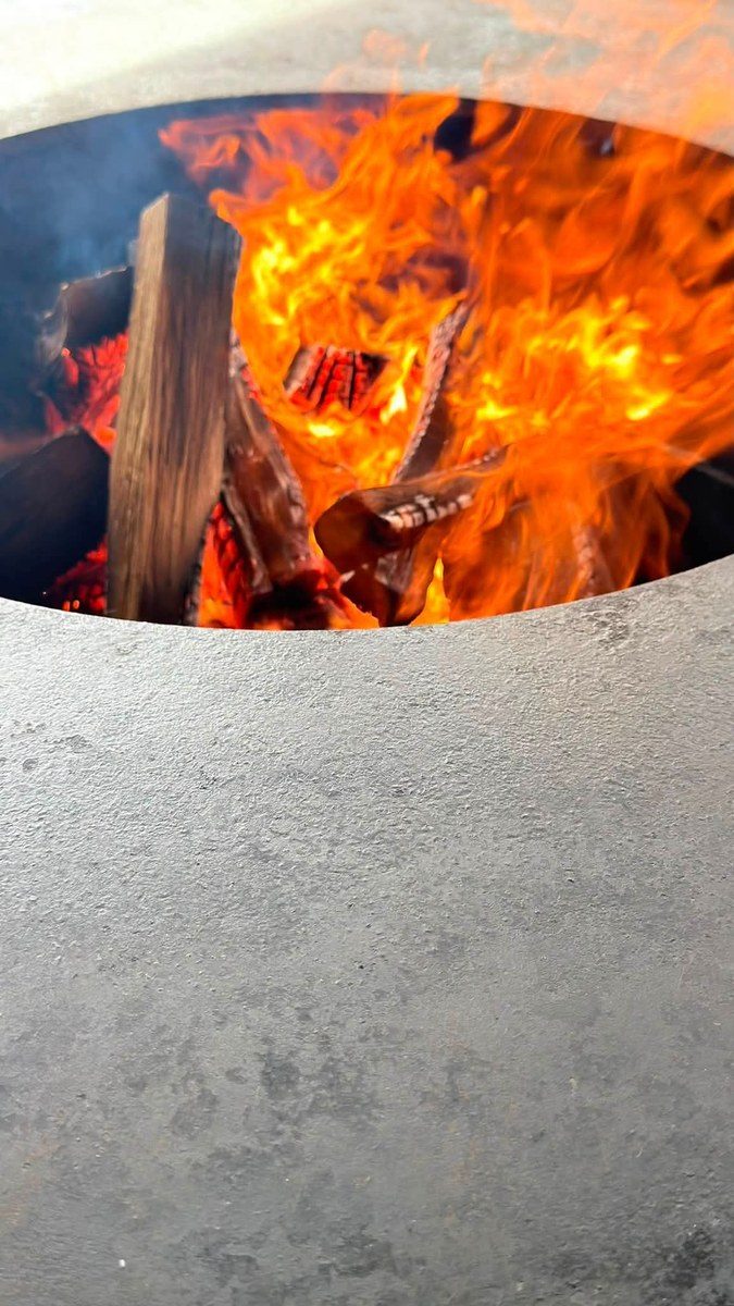 Foyer en flammes avec ses bûches, sur un plateau en acier clair