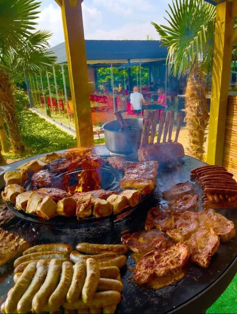 Grillades variées sur un braséro rond, palmiers en arrière-plan