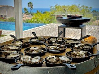 Huîtres gratinées dans des poêles en fonte posées sur la plancha, face à la mer