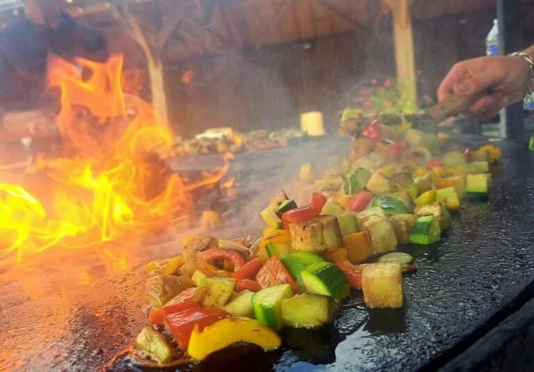 Légumes sautés sur la plancha devant de grandes flammes