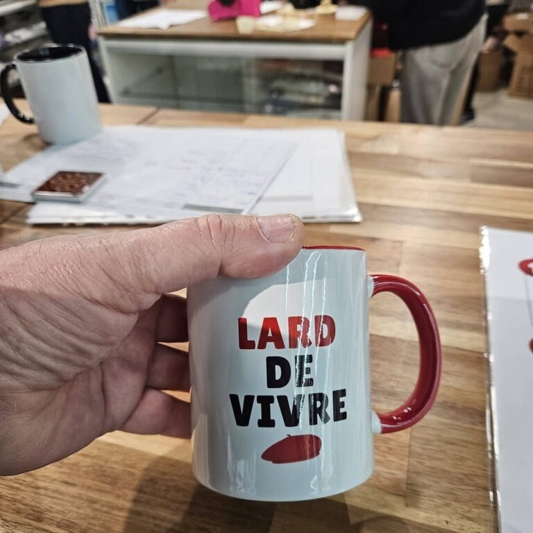 Mug « Lard de vivre » à anse rouge tenu à la main