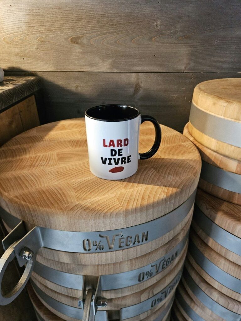 Mug « Lard de vivre » devant une pile de billots de boucher