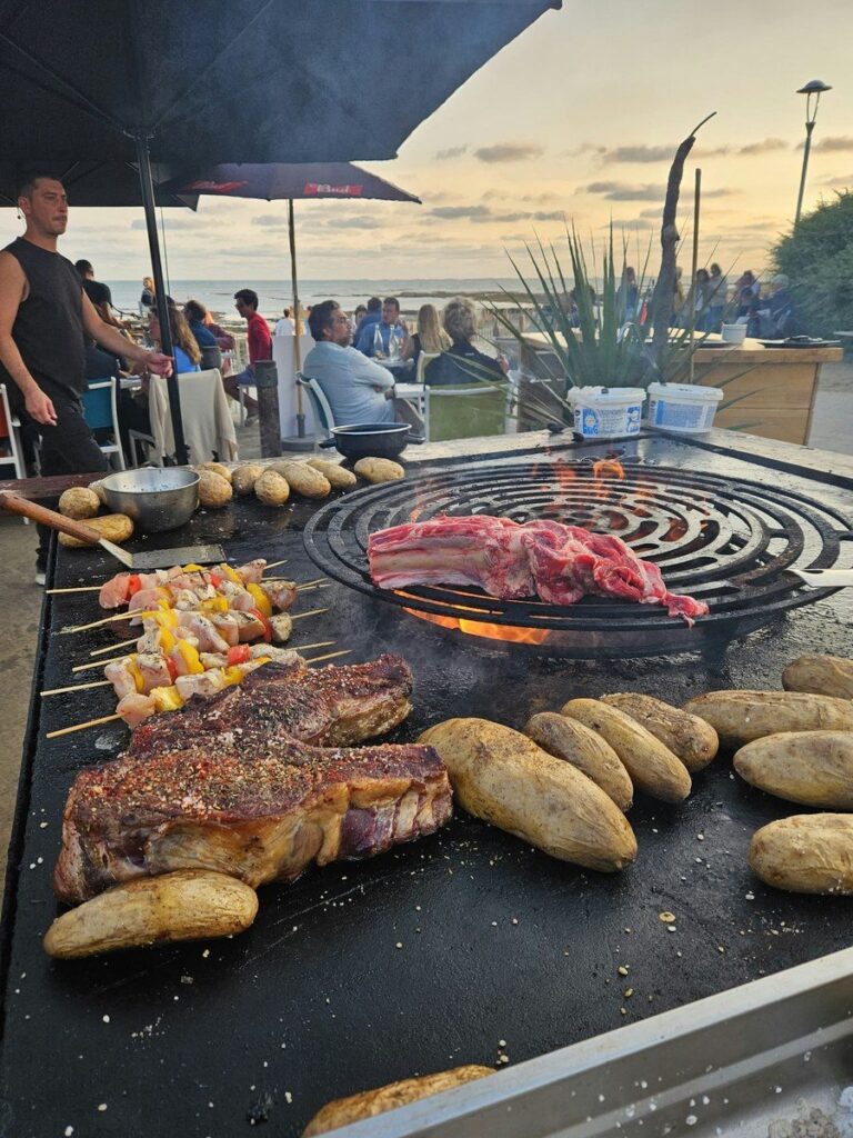Cuisinier derrière une plancha en bord de mer, côte de bœuf et pommes de terre