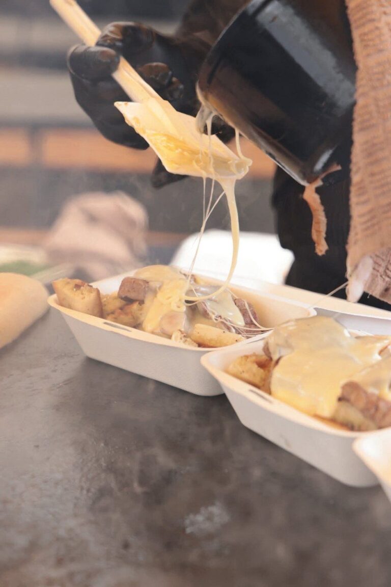 Fromage fondu versé sur des pommes de terre dans des barquettes, au bord du braséro