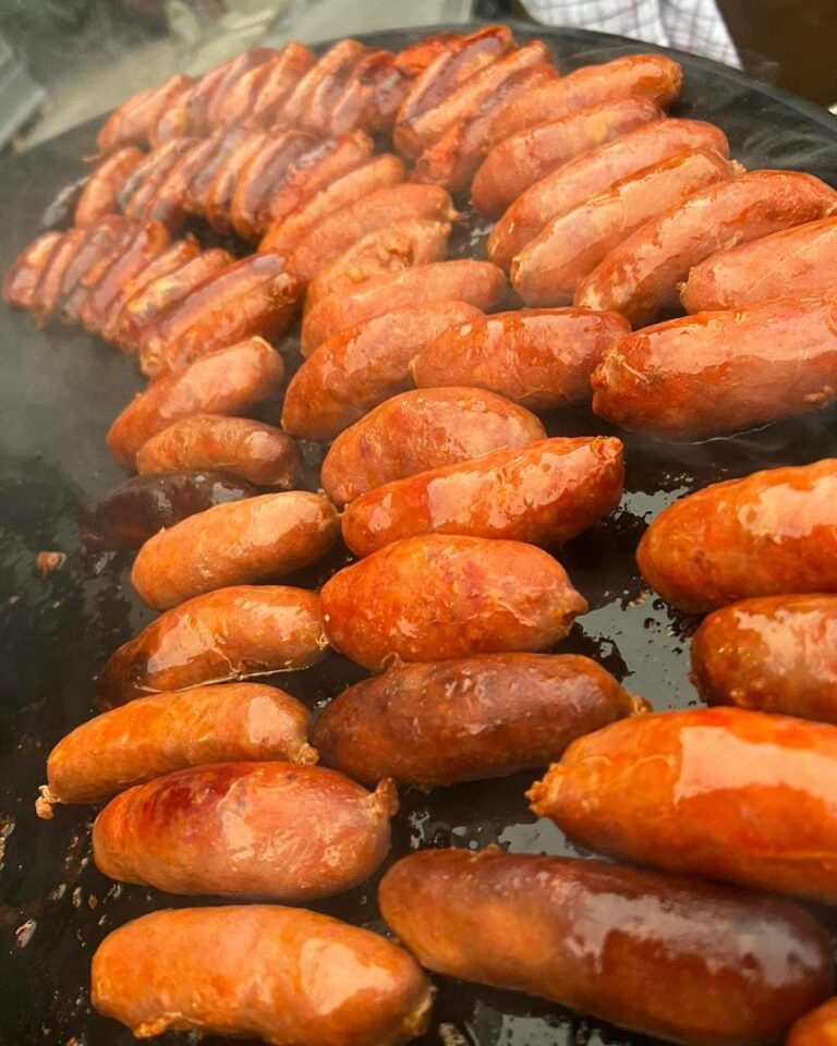 Saucisses fraîches grillées en rangs serrés sur la plancha