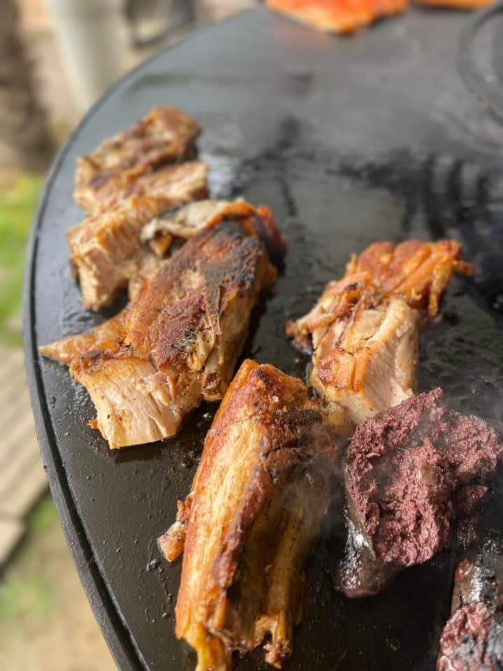 Travers de porc et boudin noir sur le plateau du braséro, pelouse en arrière-plan