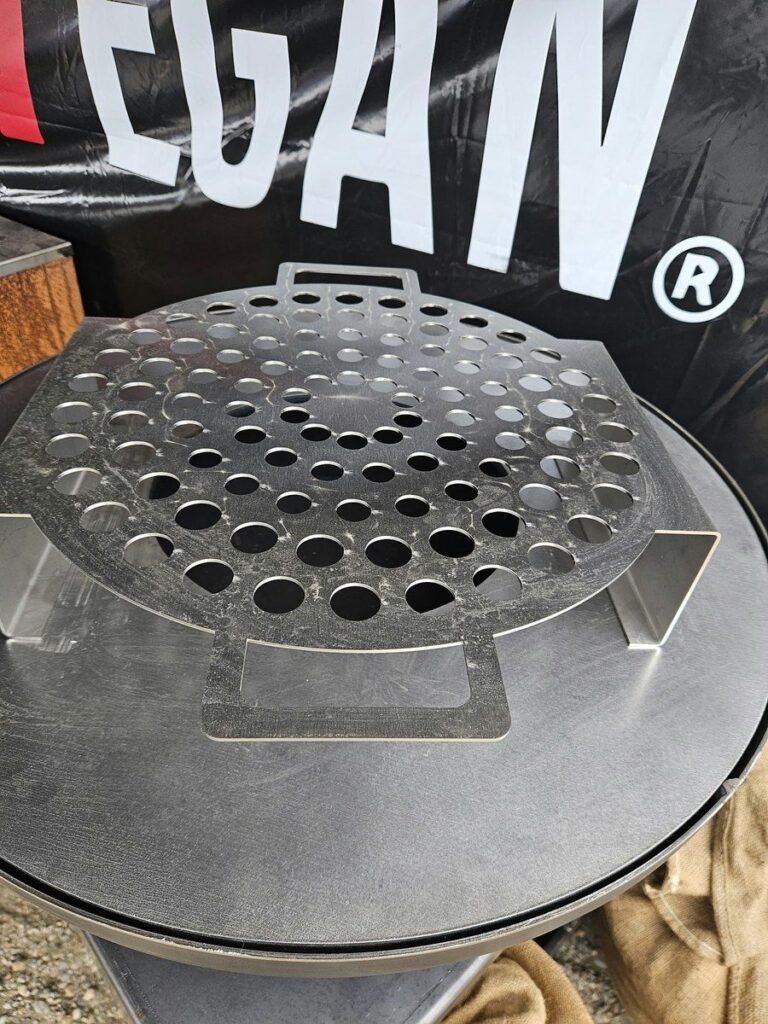 Grille à escargots en inox posée sur la plancha, banderole 0% Végan en fond