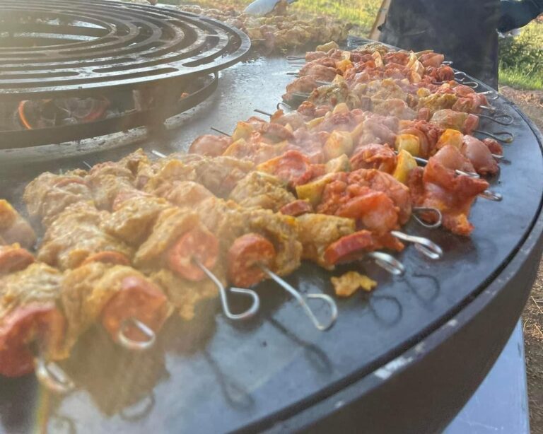 Brochettes de poulet et de poivrons alignées sur la grande plancha ronde