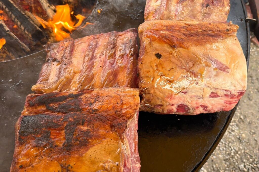 Travers de porc grillés sur le plateau d'un braséro, flammes en haut à gauche